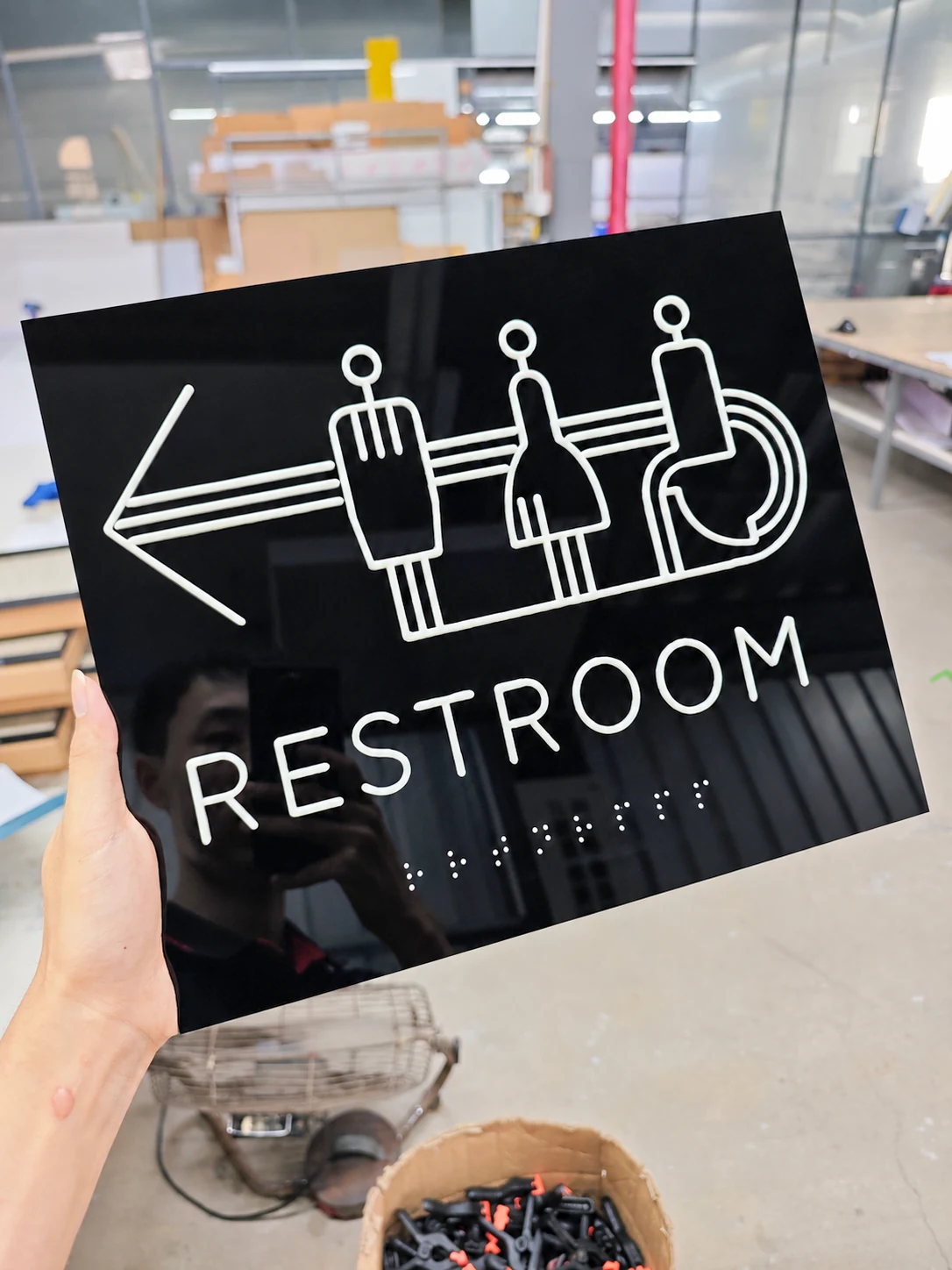 Accessible Restroom Directional Tactile Sign — Full front view highlighting the high-contrast white directional graphics and text on the black panel.