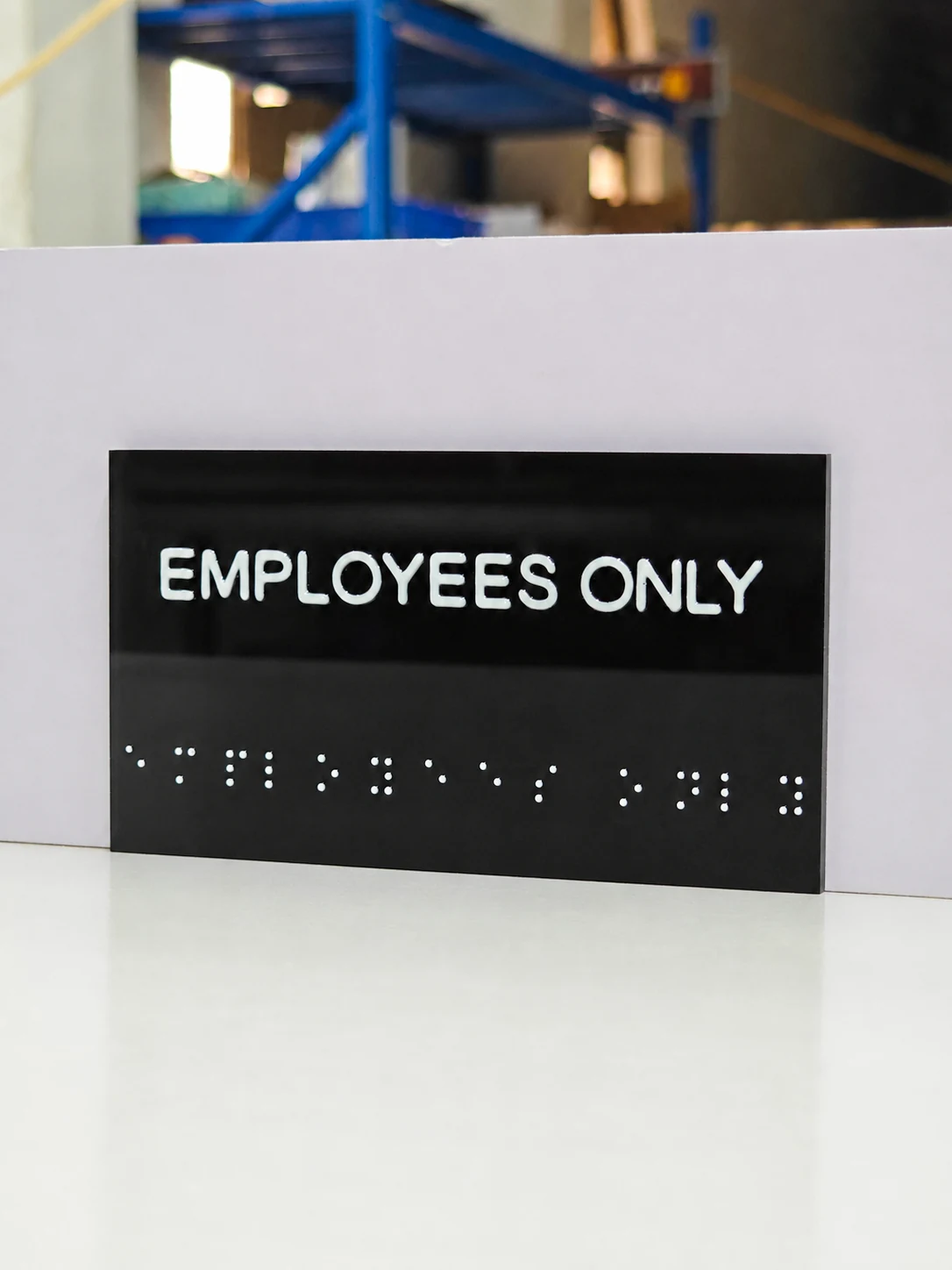 EMPLOYEES ONLY Resin Tactile Sign — Full front view of the horizontal black panel with raised white text and a row of tactile dot groups below.