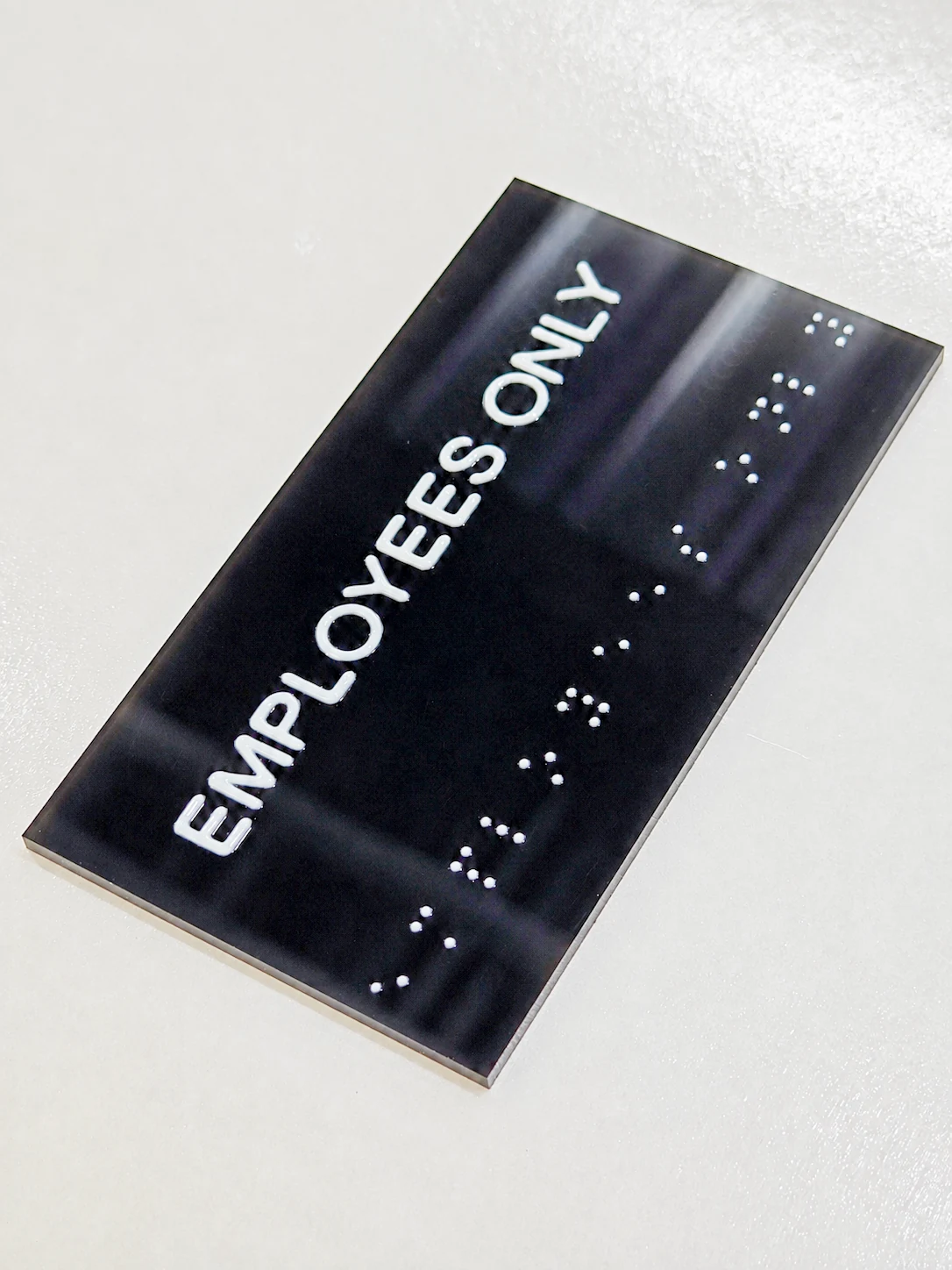 EMPLOYEES ONLY Resin Tactile Sign — Angled full view showing the complete EMPLOYEES ONLY text, tactile dots, and rectangular edges.